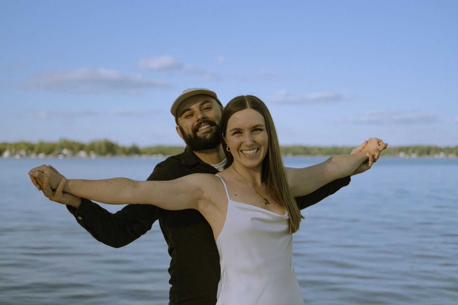 Peter and Renee with arms outstretched by the lake